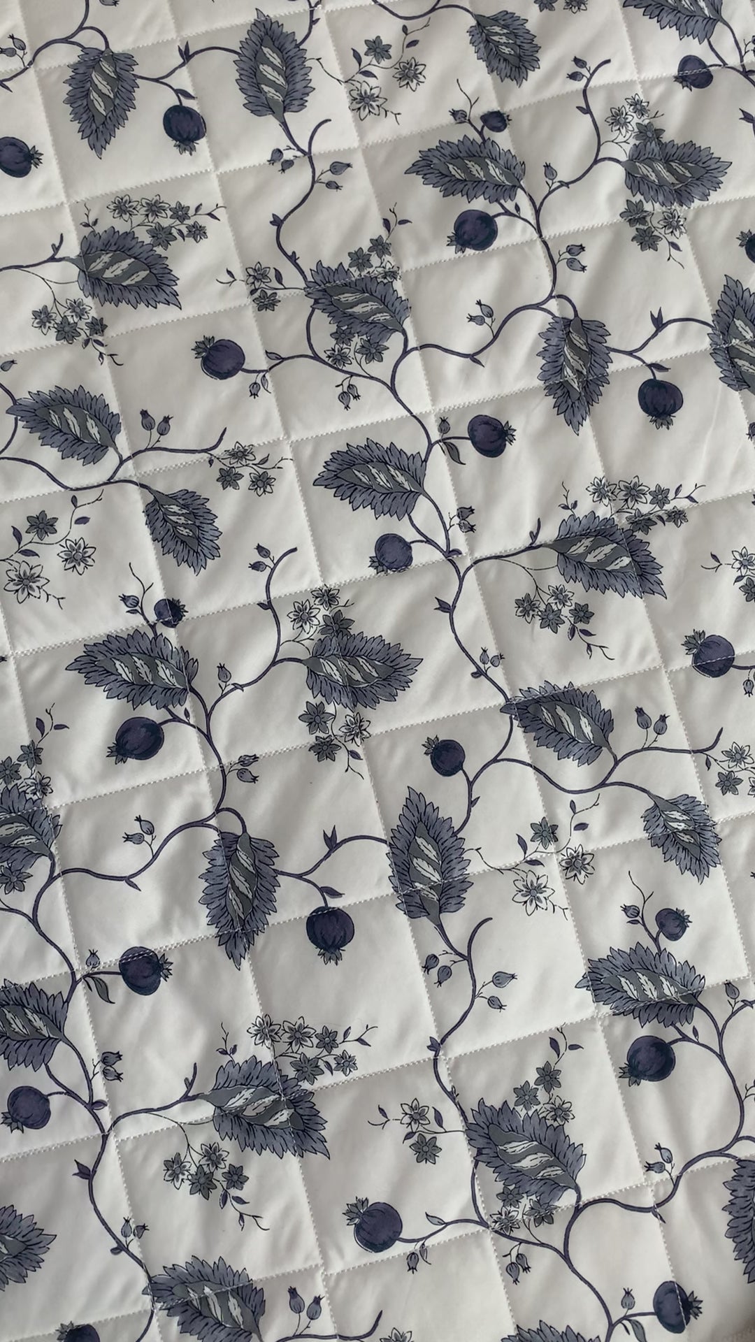 A woman lays a purple long-sleeve toddler tee that reads "Flour Child" on a quilt