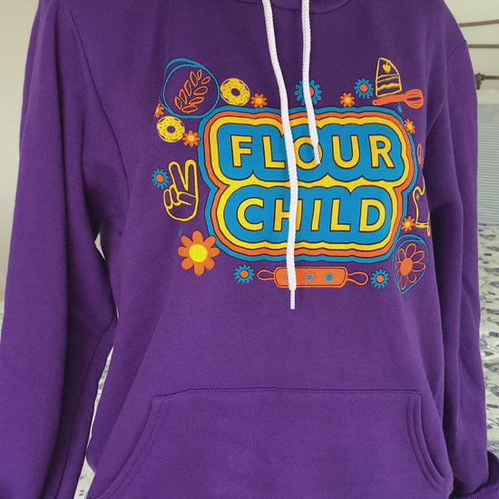 A purple hoodie that reads "Flour Child" hangs on a manikin 