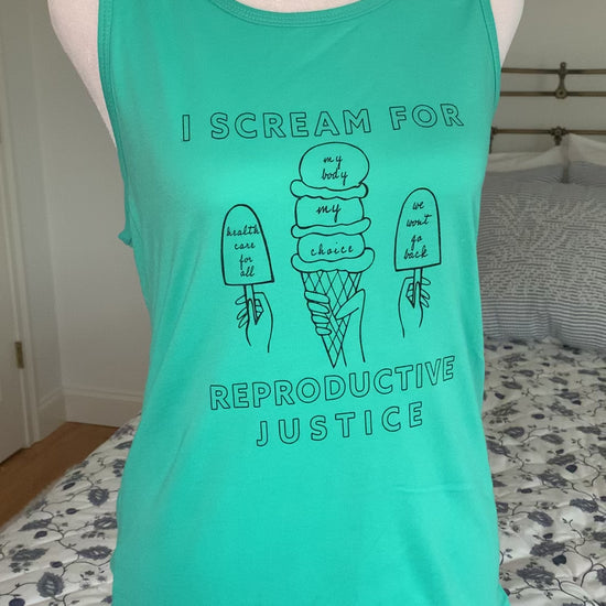 A teal tank top that reads "I scream for reproductive justice" hangs on a manikin