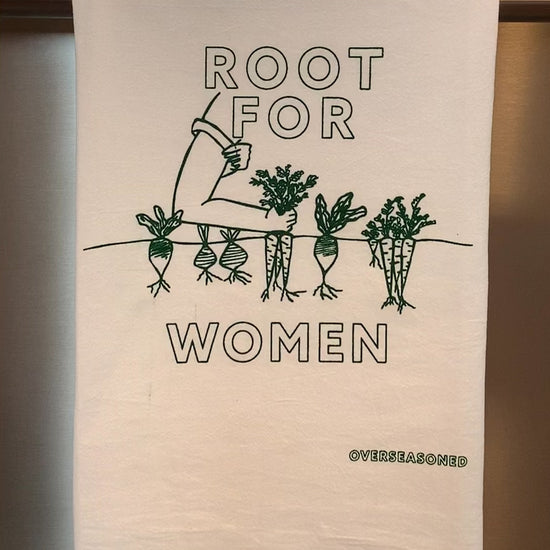 A white tea towel with "Root for Women" in green block letters hangs in a kitchen
