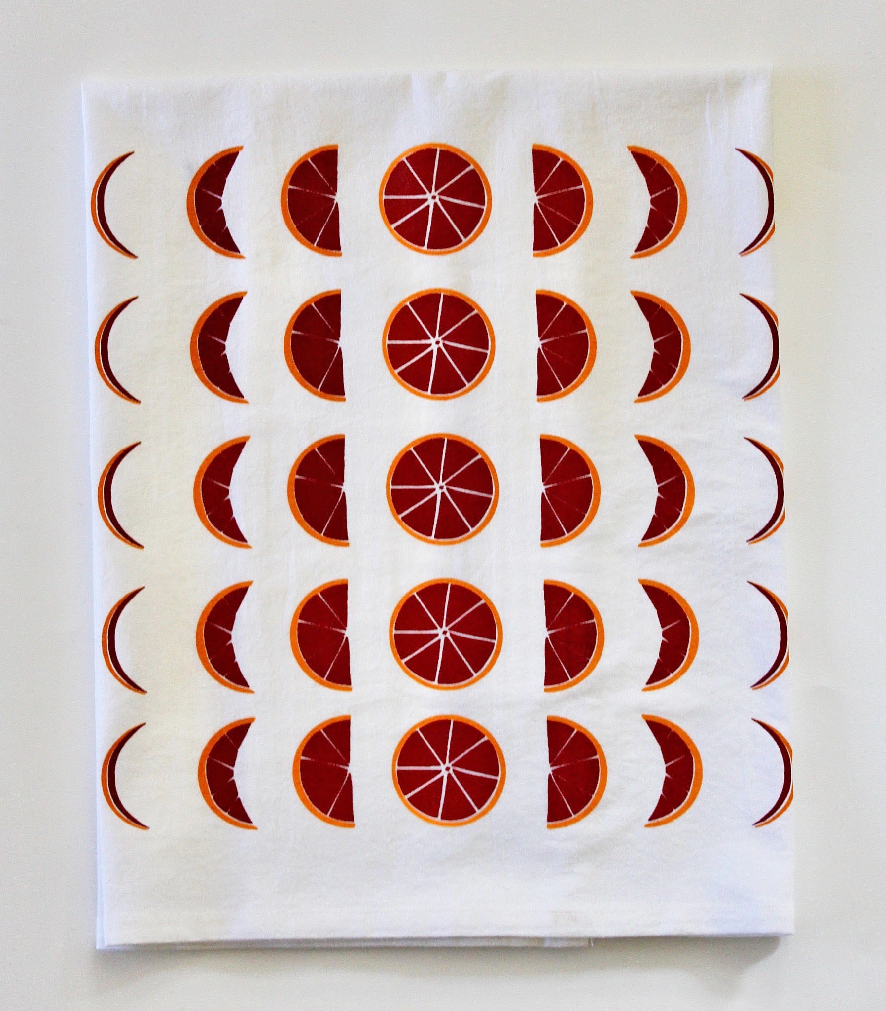 White tea towel with red and orange blood orange moon phases design