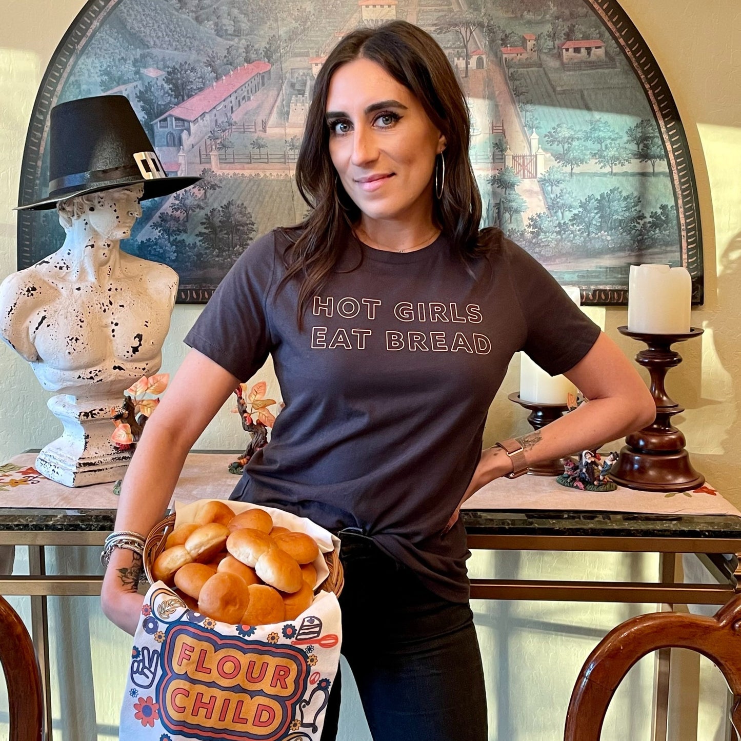 A woman wears a Hot Girls Eat Bread tee and holds a basket of rolls
