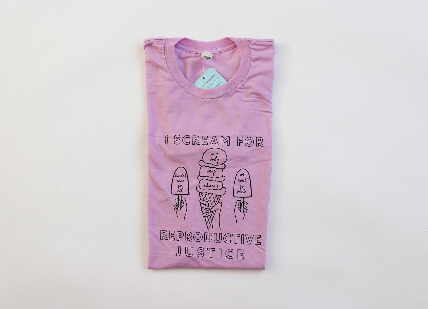 A folded lilac tee with "I Scream for Reproductive Justice" in black block letters and ice cream illustrations