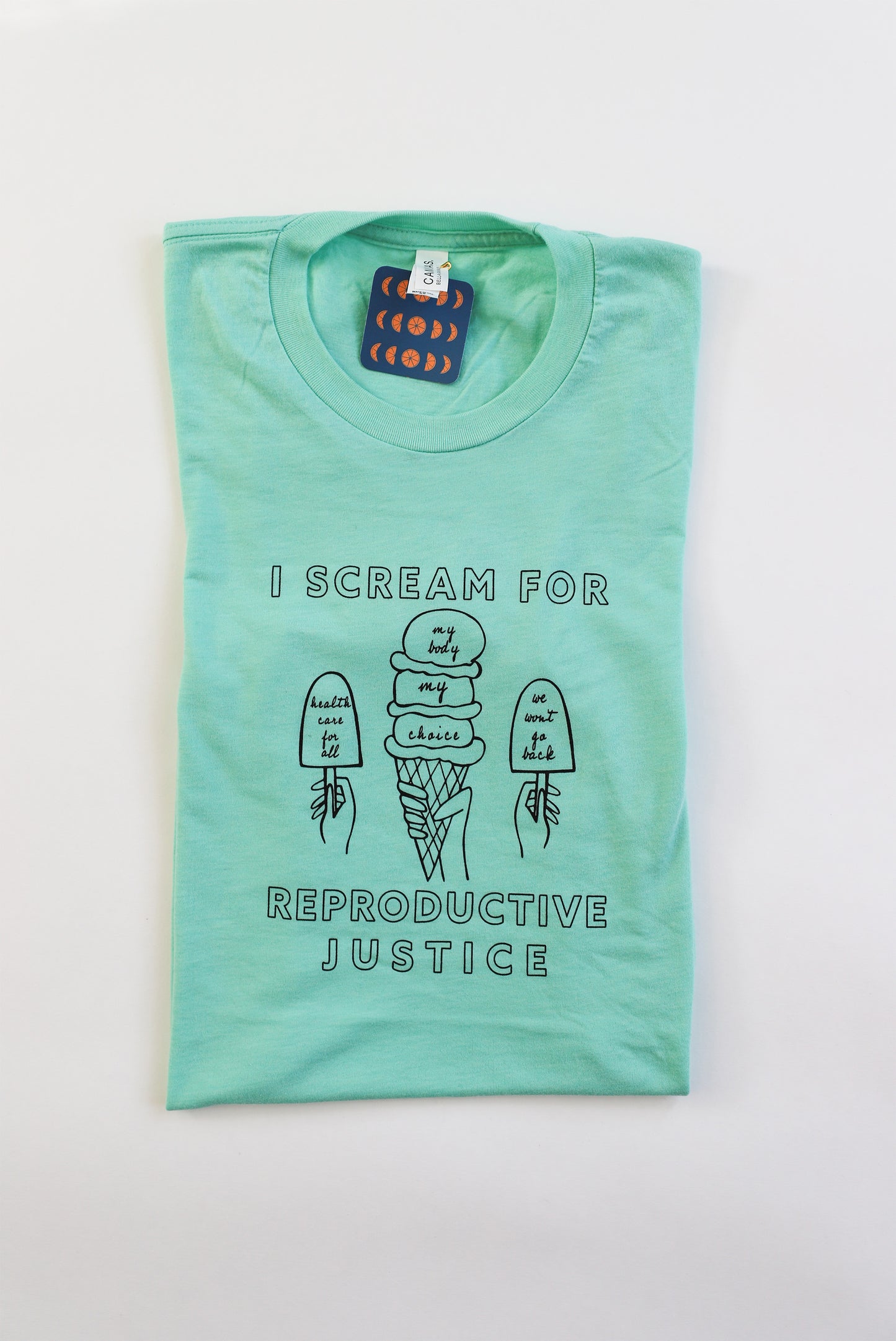 A folded mint green tea with black letters that read I Scream for Reproductive Justice and ice cream designs