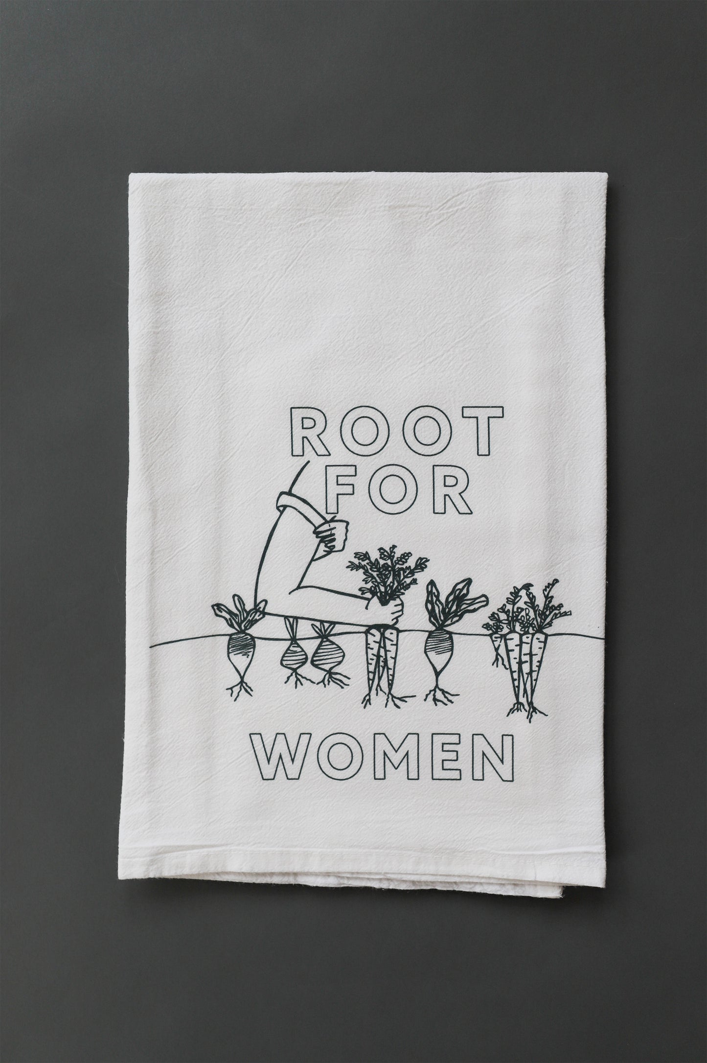 A white tea towel with green block letters that read "Root for Women" with a garden illustration