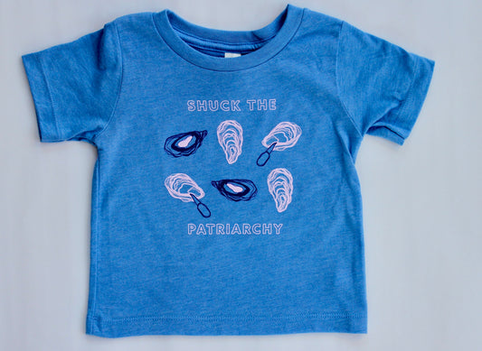 A baby sized tee in bright blue reads "Shuck the Patriarchy" in block letters with oyster illustrations