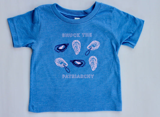 A baby sized tee in bright blue reads "Shuck the Patriarchy" in block letters with oyster illustrations