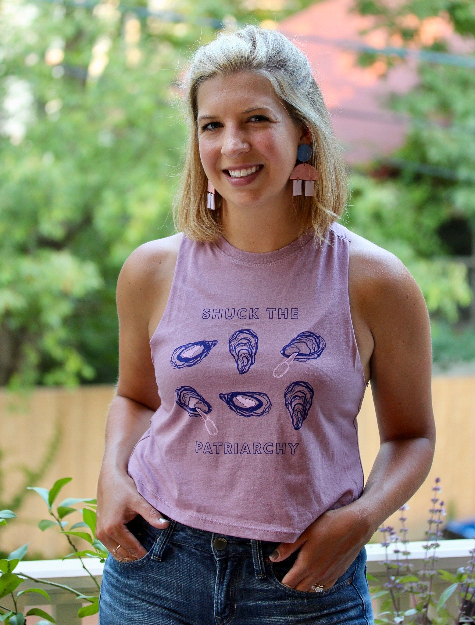 A woman wears a "Shuck the Patriarchy" cropped tank with jeans
