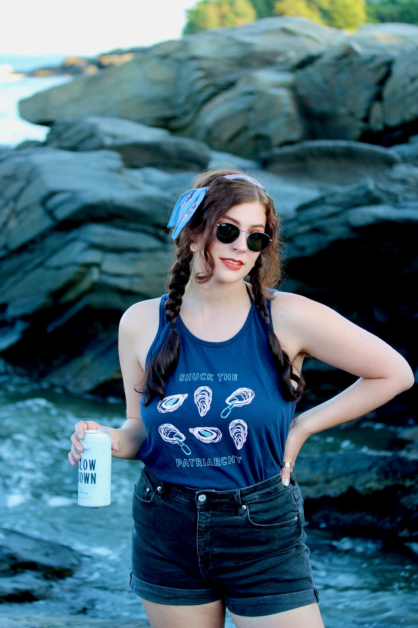 A woman wears a navy blue "Shuck the Patriarchy" at the beach