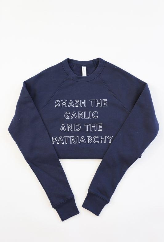 A navy blue crewneck sweatshirt reads "Smash the Garlic and the Patriarchy" in white block letters