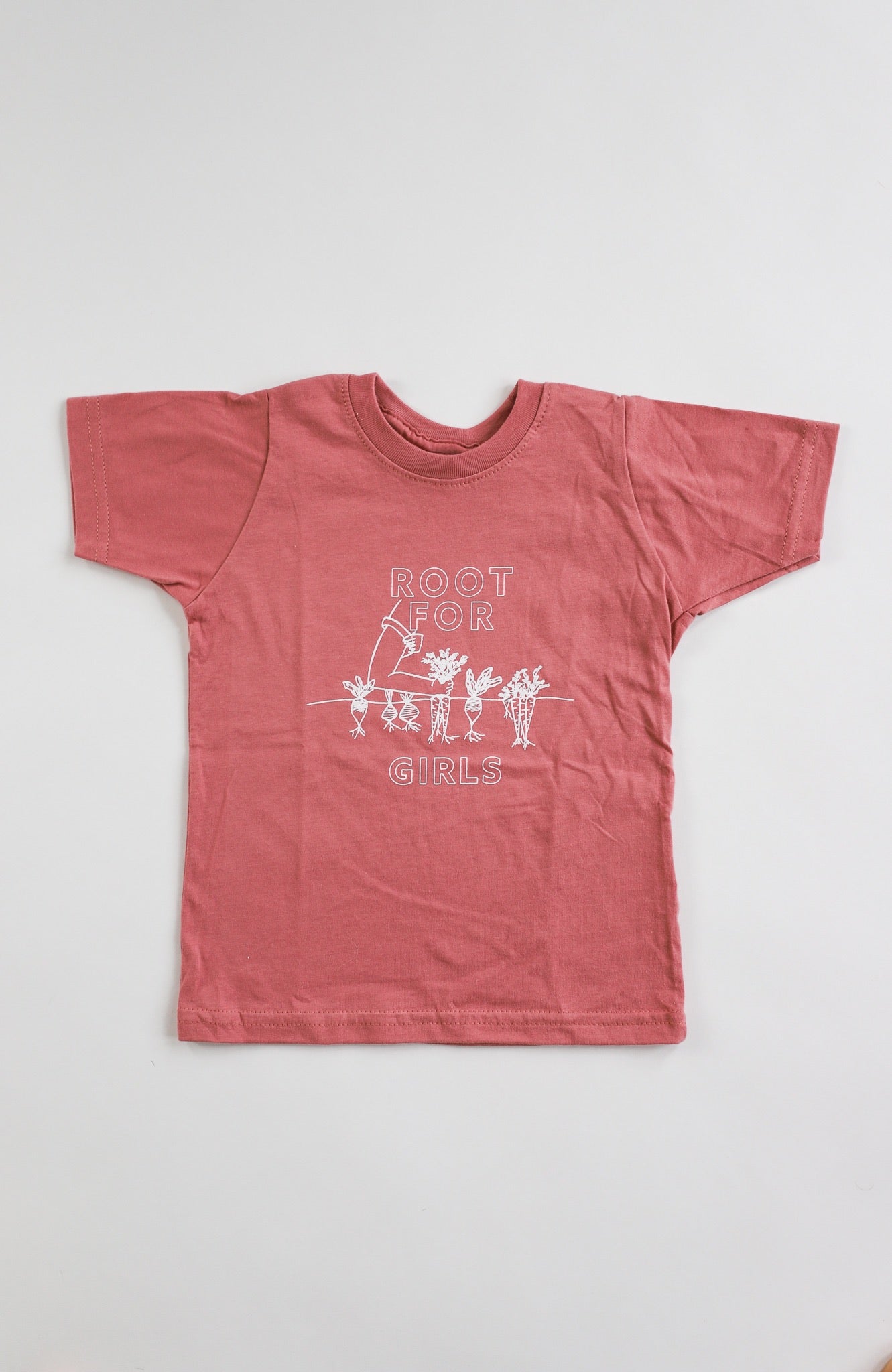 A mauve toddler tee with the words "Root for Girls" in white block letters and a garden illustration