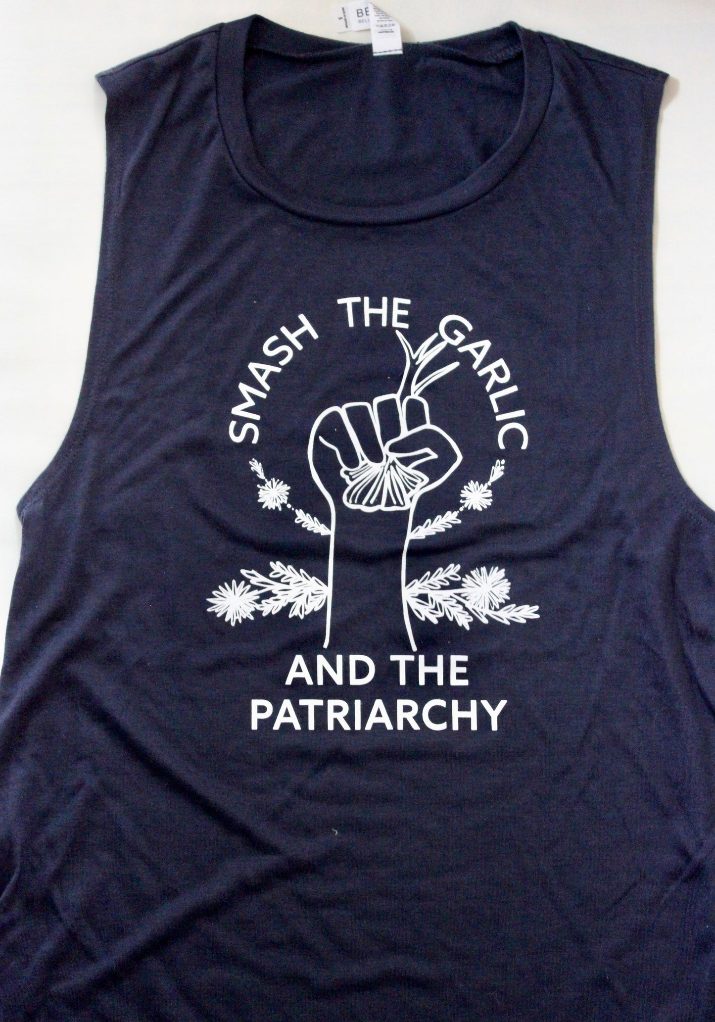 A navy blue tank top reads "Smash the Garlic and the Patriarchy" in white block letters with an illustration of a hand holding garlic