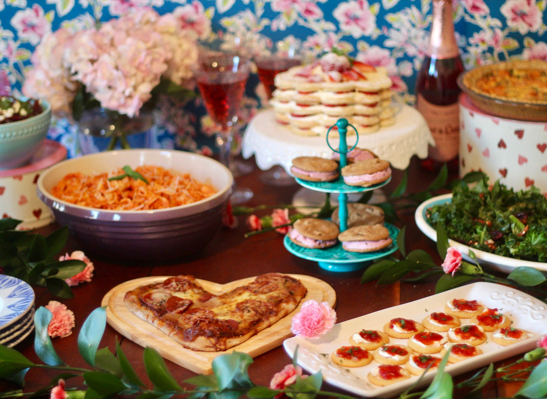 A Galentines Party spread of pasta and pink sauce, heart-shaped pizza, a waffle tower cake, sparkling rose and homemade ice cream sandwiches