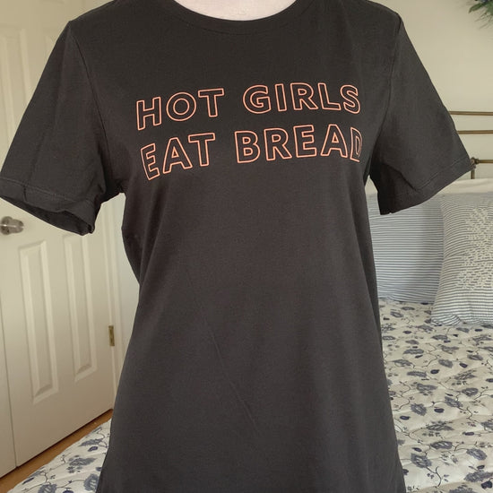 A dark grey tee that reads "Hot Girls Eat Bread" hangs on a manikin 