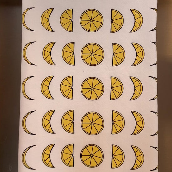 A white tea towel with lemon moon phases designs hangs in a kitchen
