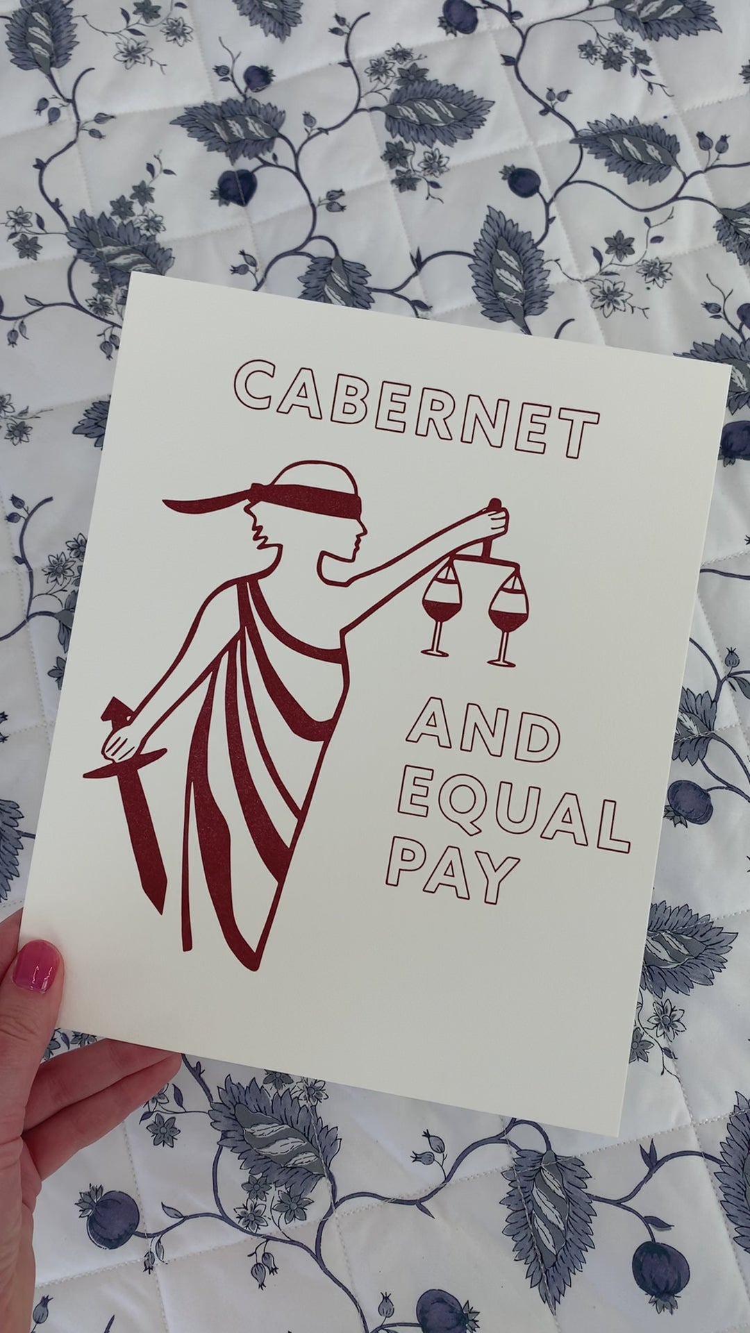 An art print with the image of Lady Justice and the words "Cabernet and Equal Pay"