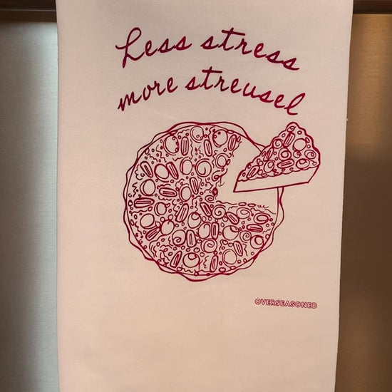 A white tea towel that reads "Less stress more streusel" hangs in a kitchen