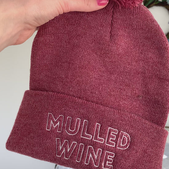 A heather wine colored beanie reads "Mulled Wine" in white embroidery