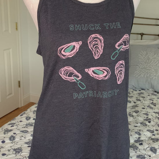 A heather navy tank that reads "Shuck the Patriarchy" hangs on a manikin