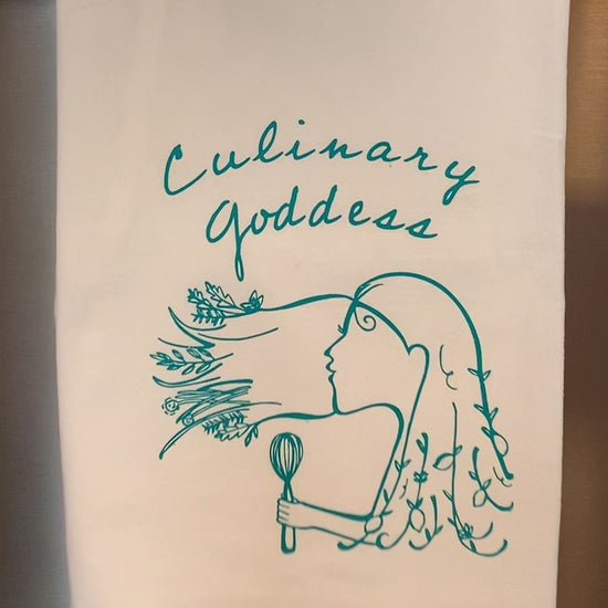 A white tea towel that reads "Culinary Goddess" in teal lettering hangs in a kitchen