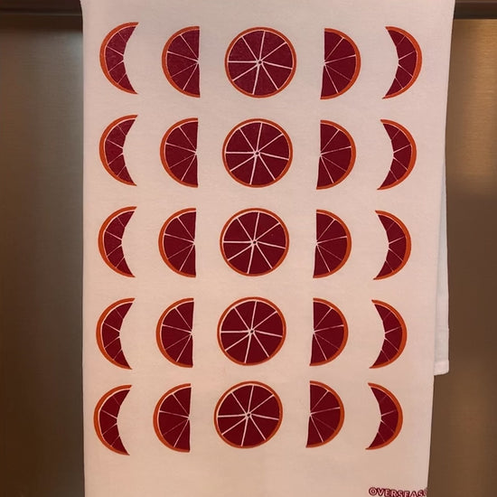 A white tea towel with blood orange moon design hangs on a bar