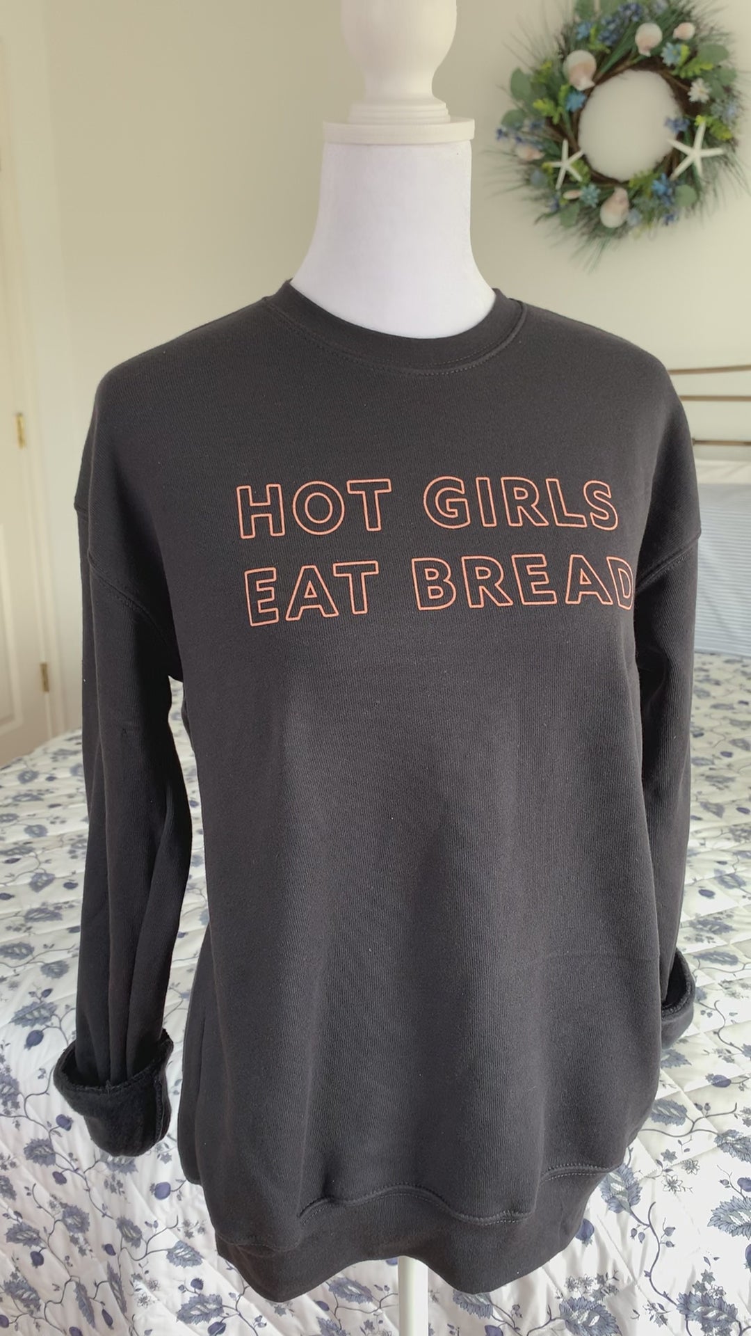 A dark grey sweatshirt that reads "Hot Girls Eat Bread" hangs on a manikin 