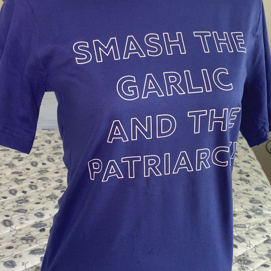 A bright blue tee that reads "Smash the Garlic and the Patriarchy" in white block letters hangs on a manikin