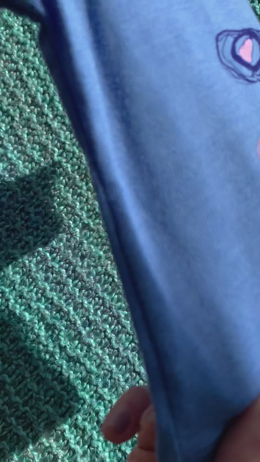 A baby tee that reads "Shuck the Patriarchy" on top of a blanket