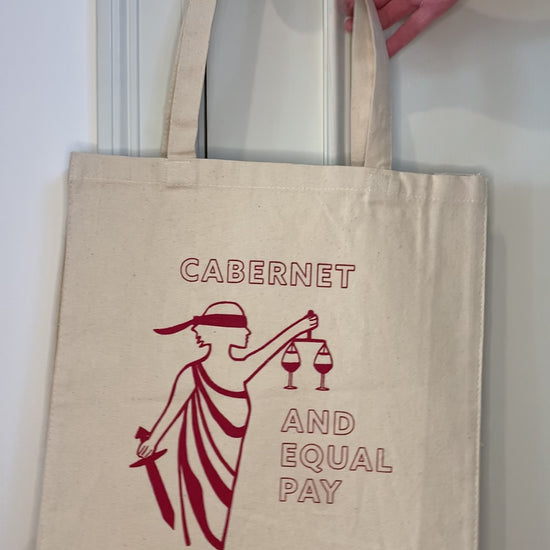 A canvas tote that reads "Cabernet and Equal Pay" hangs from a doorknob
