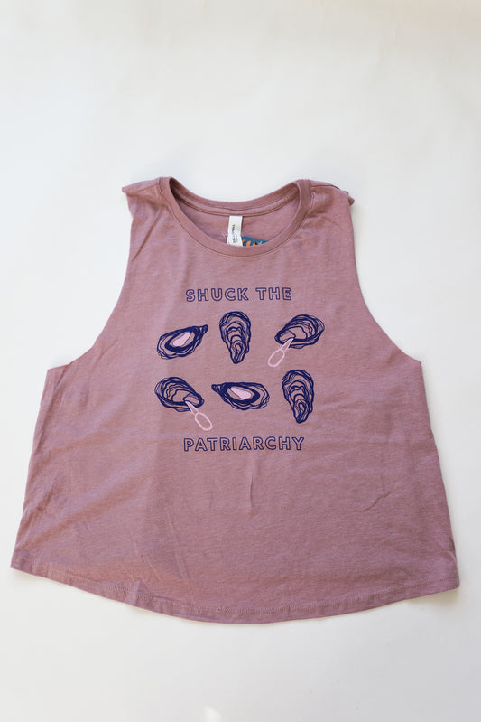 A women's mauve cropped tank reads "Shuck the Patriarchy" in block letters with oyster designs