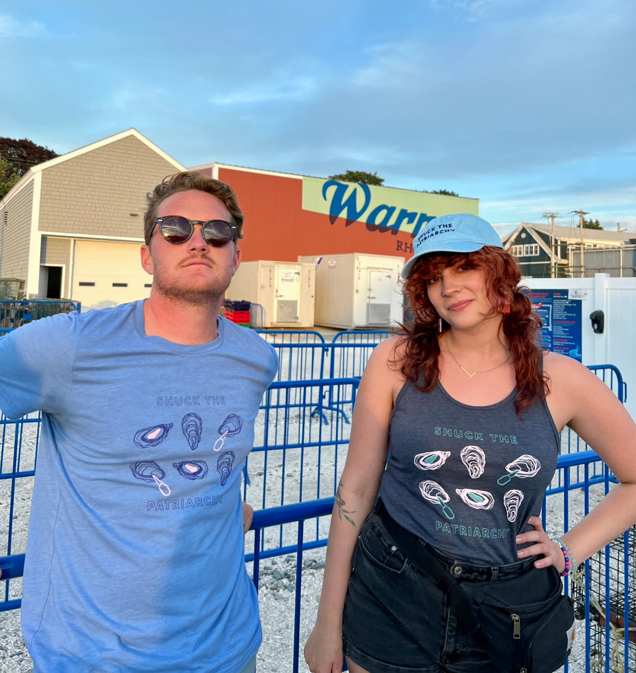 A man wears a "Shuck the Patriarchy" t-shirt next to a woman wearing a "Shuck the Patriarchy" tank top
