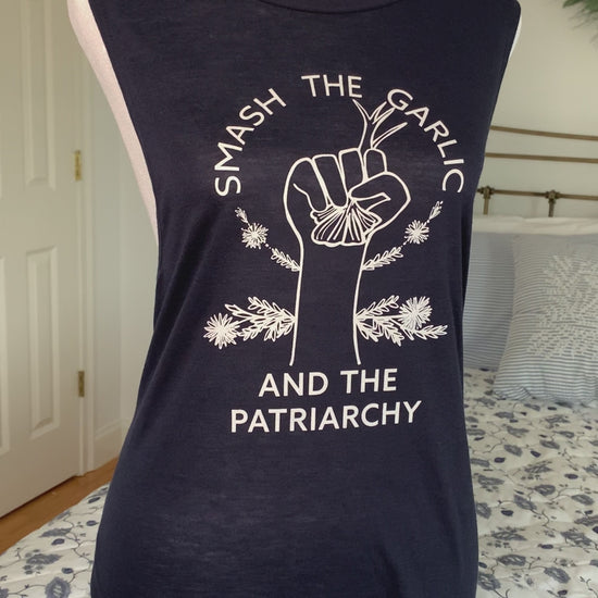 A navy tank with the words "Smash the Garlic and the Patriarchy" and a garlic illustration hangs on a manikin