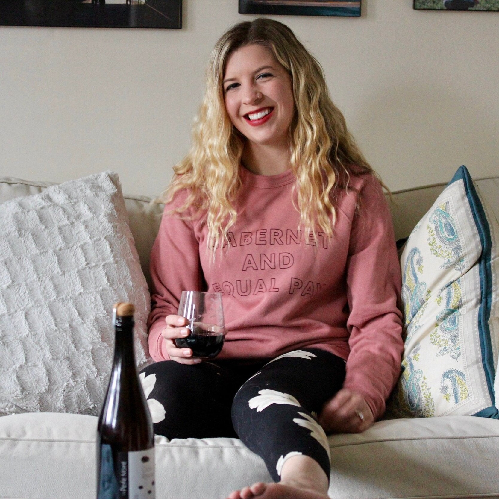 Woman wearing mauve sweatshirt and leggings drinking wine