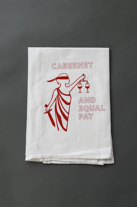 White tea towel with red Lady Justice design and the words "Cabernet and Equal Pay"