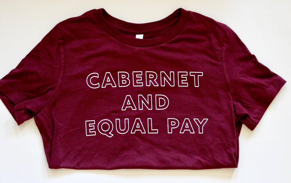 Maroon t-shirt with white block letters that say "Cabernet and Equal Pay"
