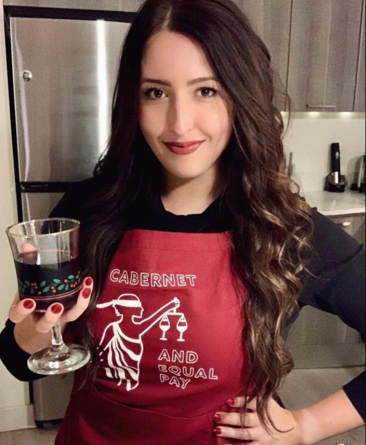Woman wearing red apron holding a glass of red wine