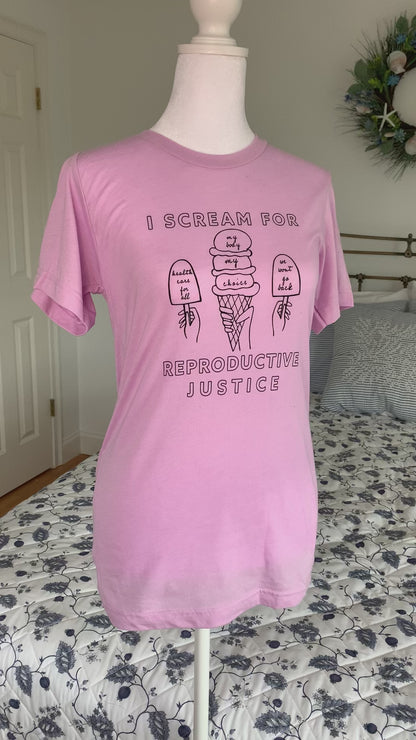 A lilac t-shirt that reads "I scream for reproductive justice" hangs on a manikin