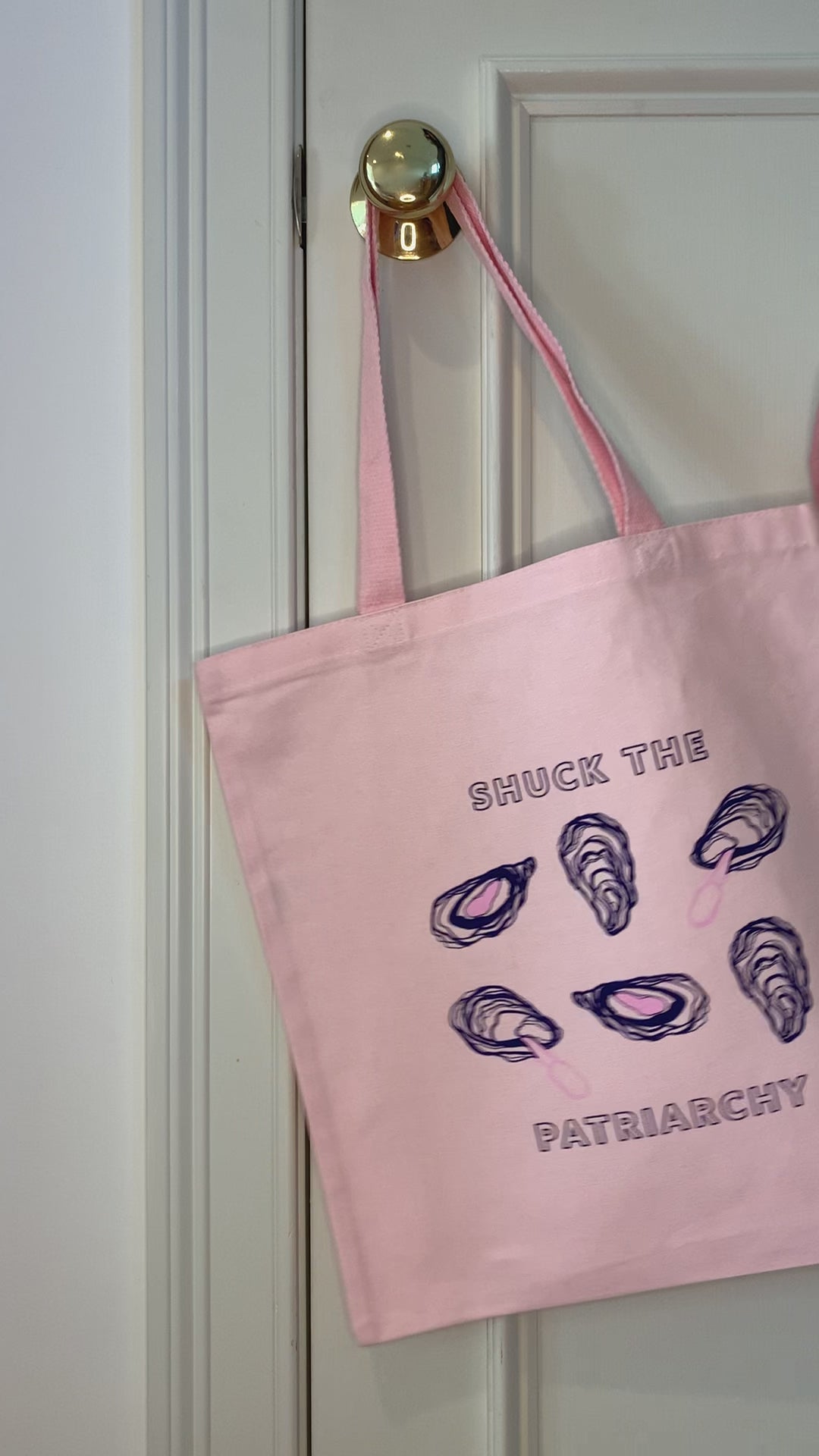 A pink tote that reads "Shuck the Patriarchy" hangs on a doorknob
