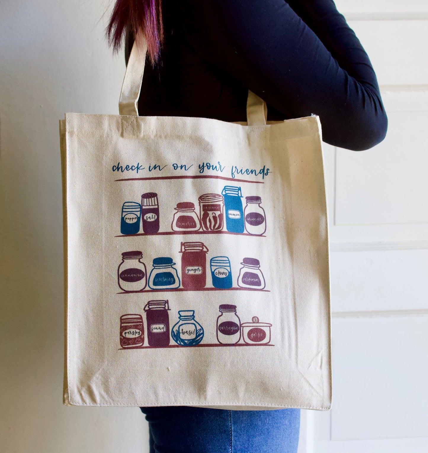 Woman wearing tote that says "Check in on your friends" with cute kitchen design