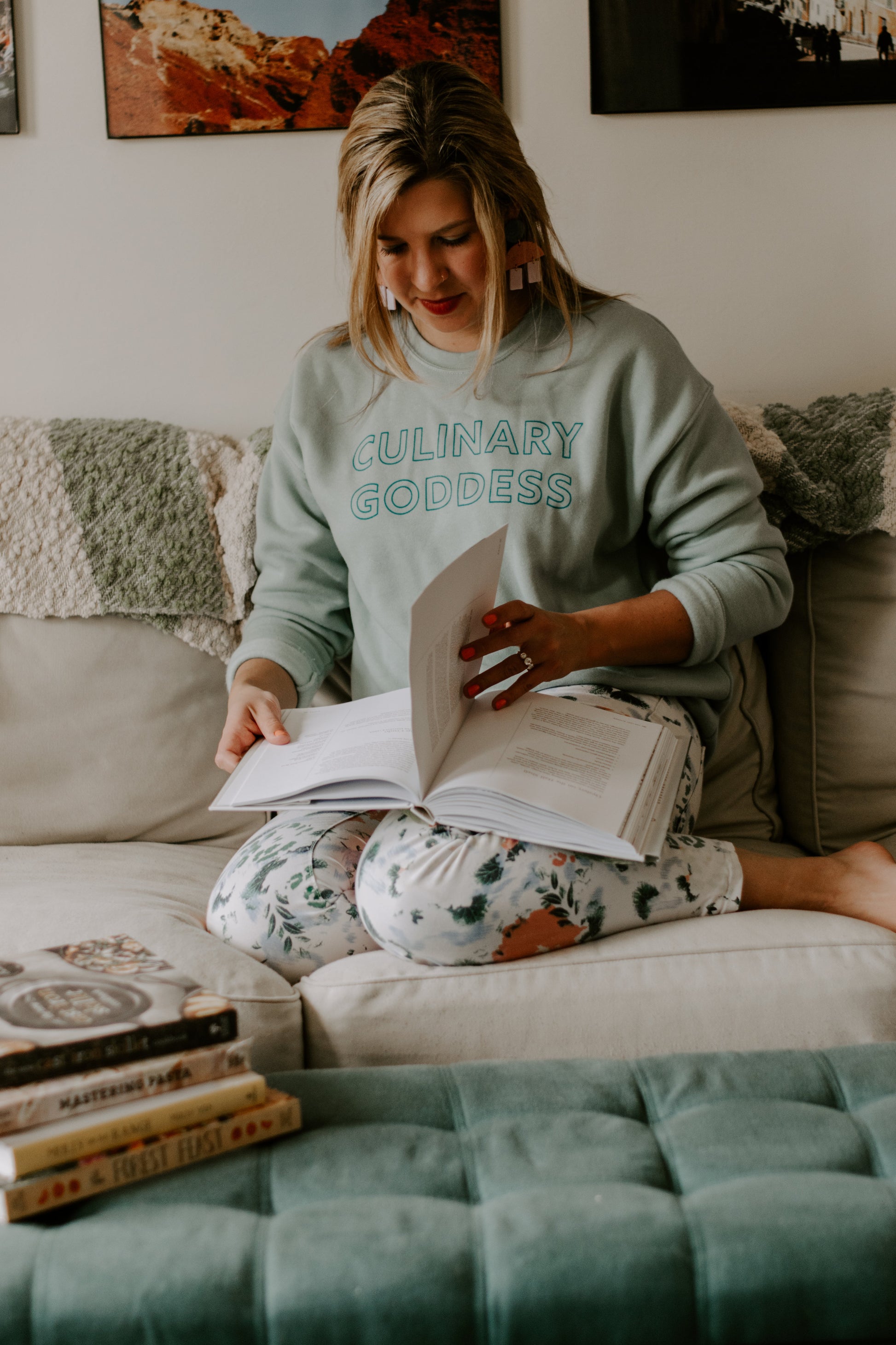 Woman wearing dusty blue crewneck reading a cookbook