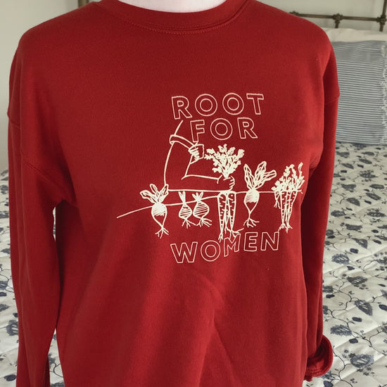 A red sweatshirt that reads "Root for Women" hangs on a manikin