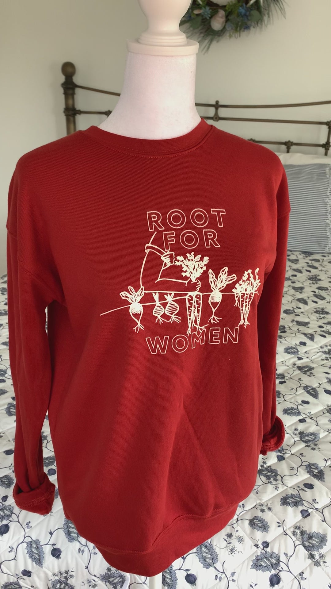 A red sweatshirt that reads "Root for Women" hangs on a manikin