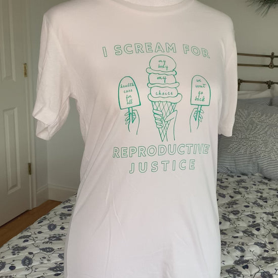 A white t-shirt that reads "I scream for reproductive justice" hangs on a manikin