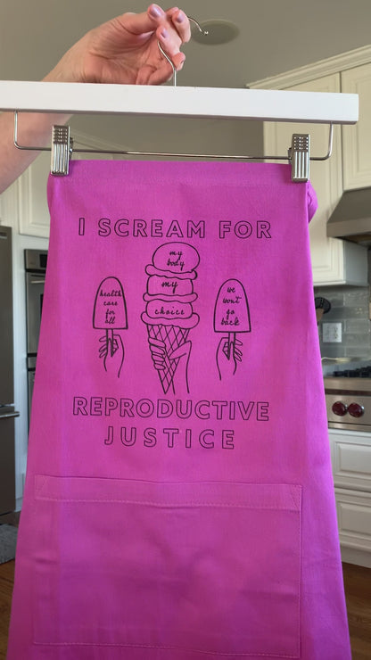 A pink apron that reads "I scream for reproductive justice" hangs on a hanger