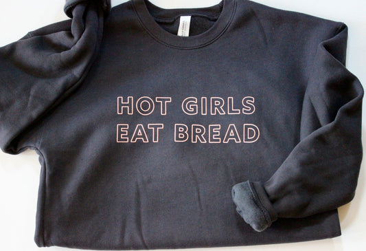 A dark grey crewneck sweatshirt with the words Hot Girls Eat Bread in pink block letters