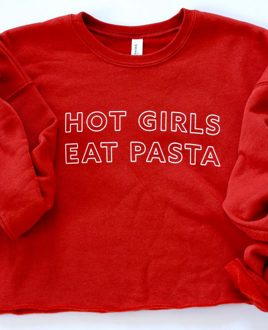 A bright red cropped sweatshirt with a raw hem and the words Hot Girls Eat Pasta in white block letters