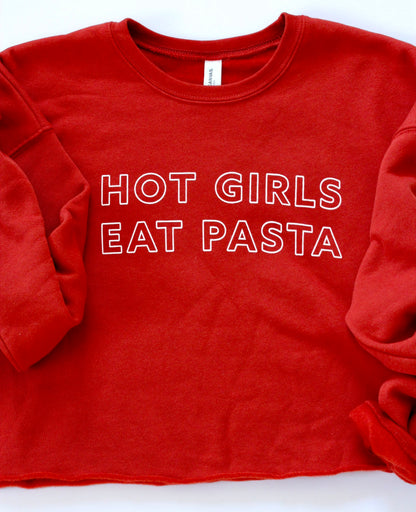 A bright red cropped sweatshirt with a raw hem and the words Hot Girls Eat Pasta in white block letters
