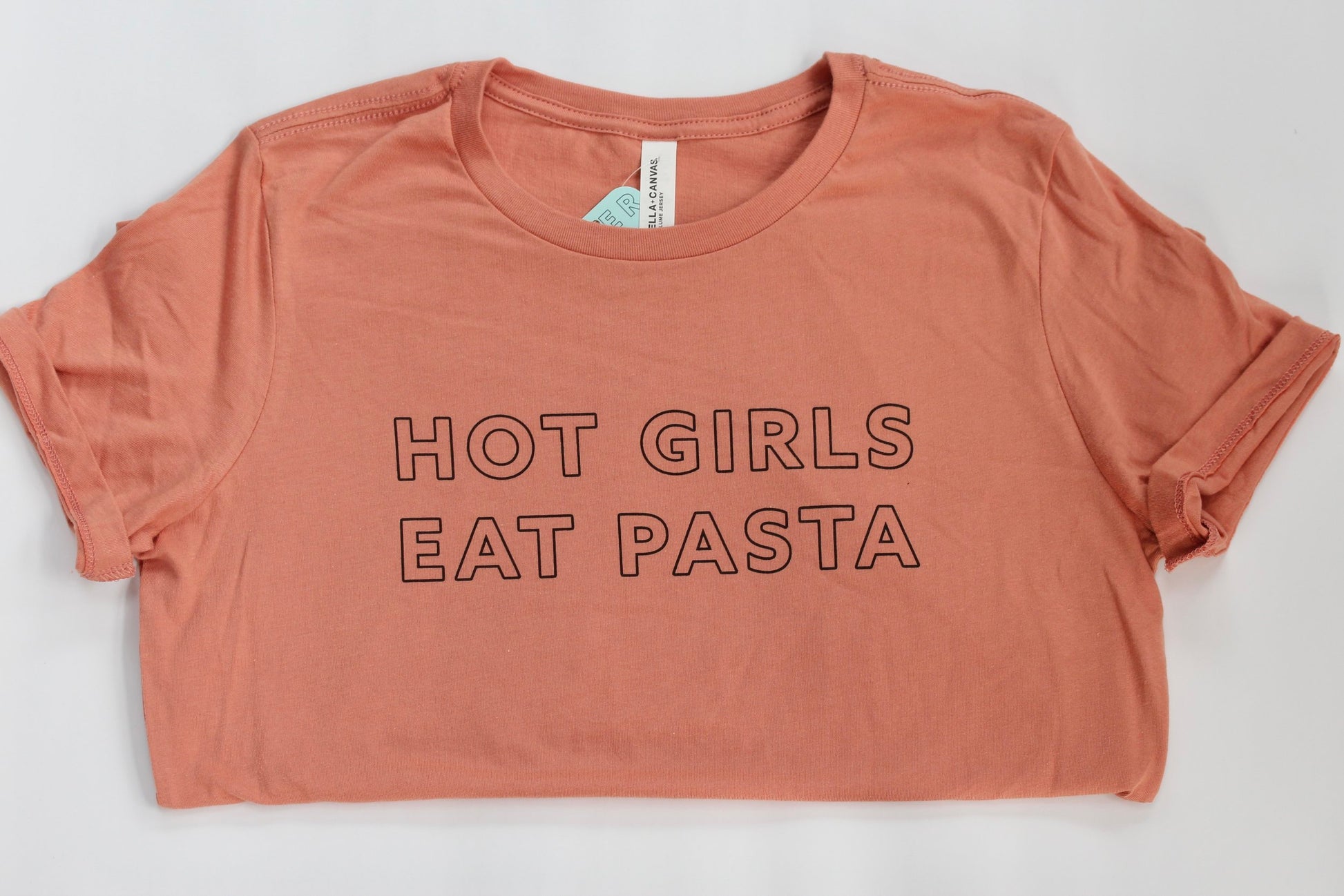 A peach colored women's tee with the words Hot Girls Eat Pasta in black block letters