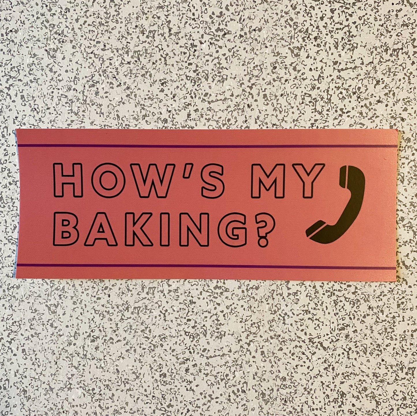 A funny bumper sticker with the words "How's my baking?" in black block letters and a phone icon