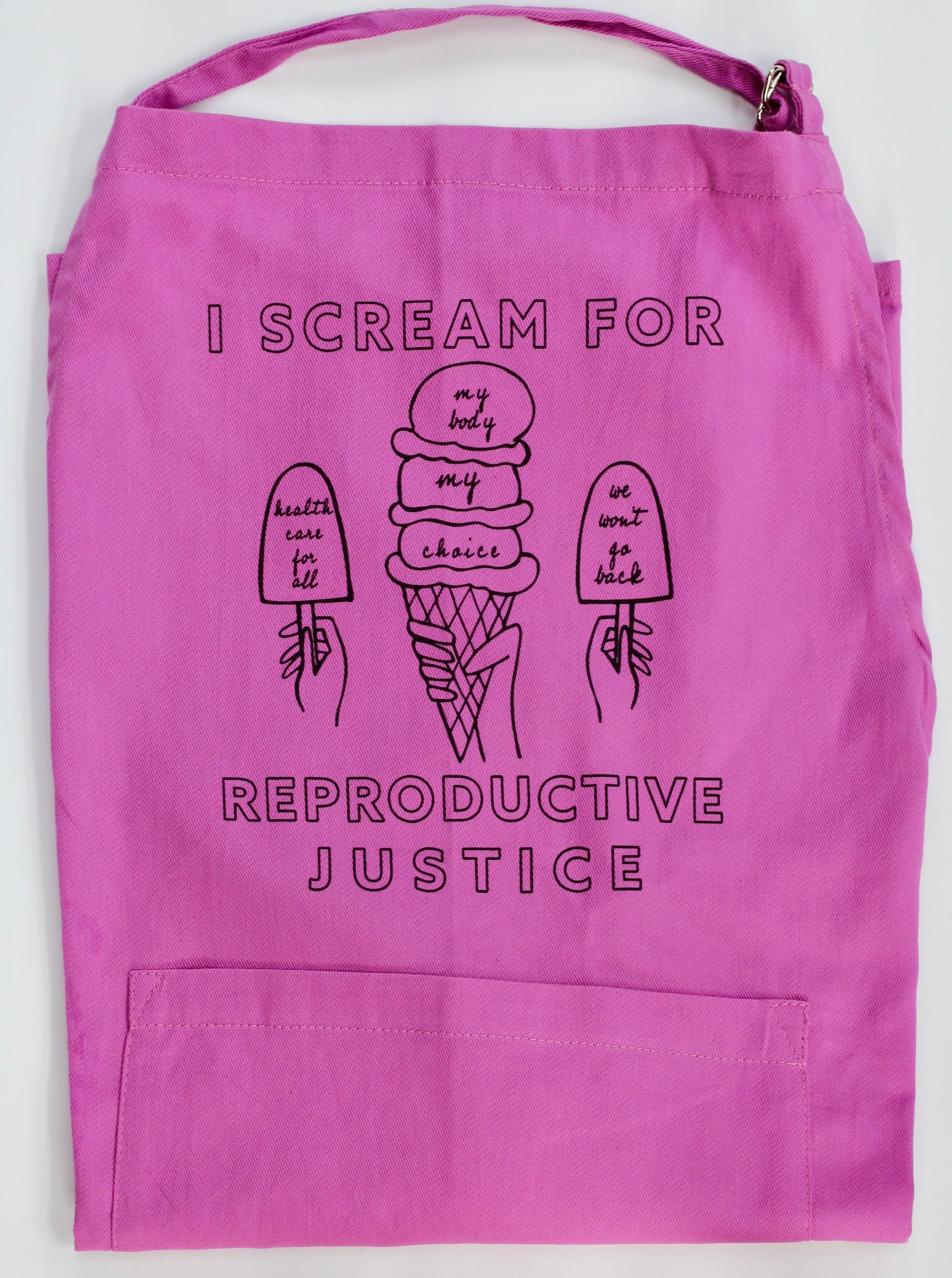 A folded bright pink apron with the words "I Scream for Reproductive Justice" in black block letters and ice cream illustrations 